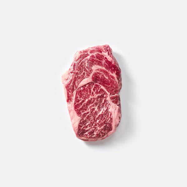 Raw steak with marbling on a light gray background